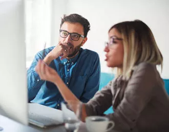 lady and man look at computer monitor